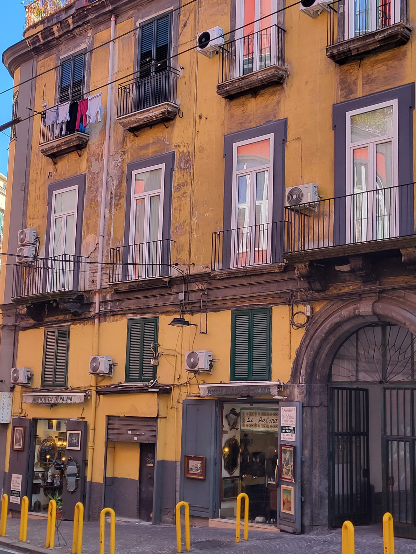 Palazzo storico giallo con balconi e bottega di antiquariato nel Centro Storico di Napoli